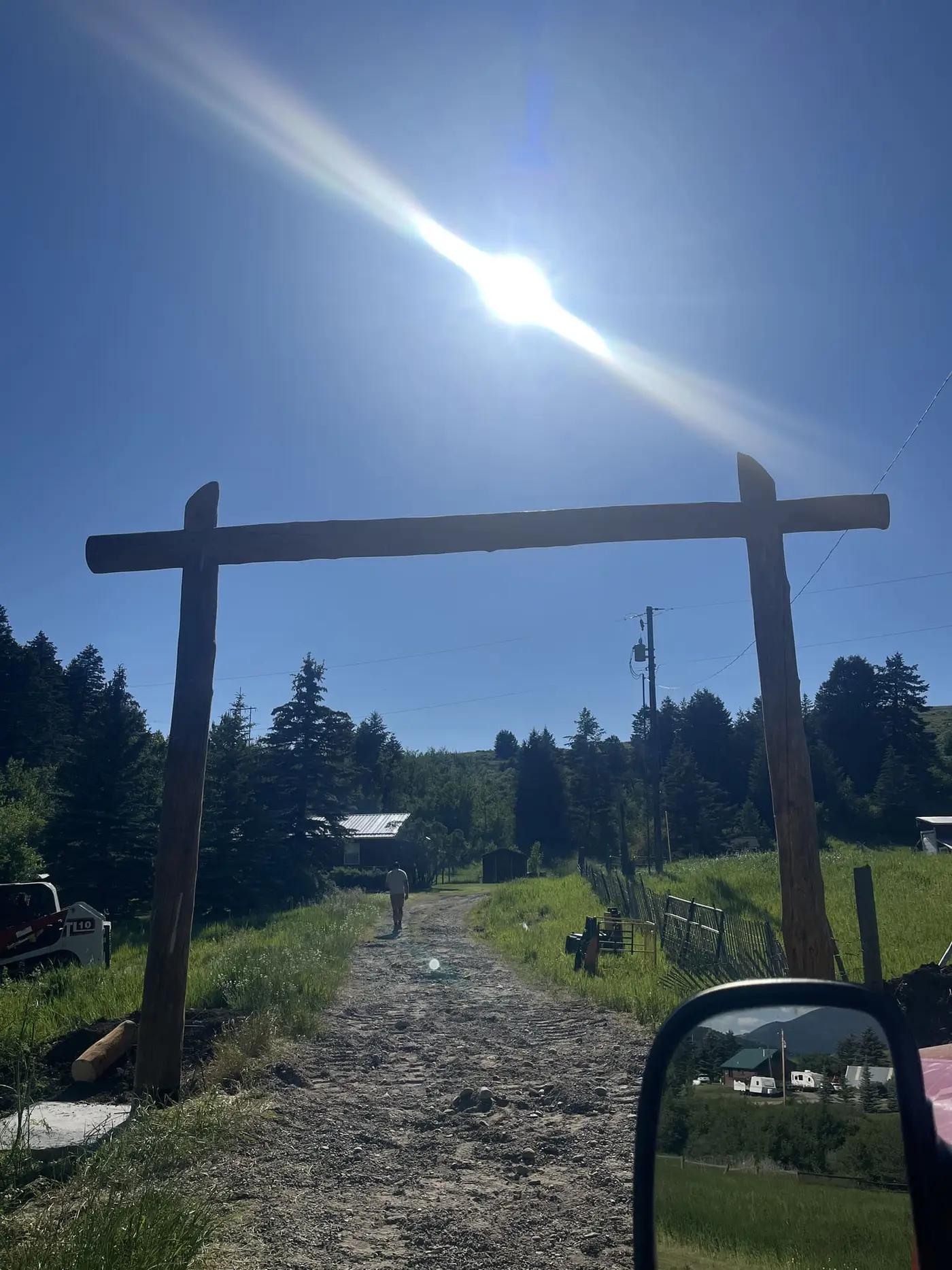 Log archway from the road with mountains beyond