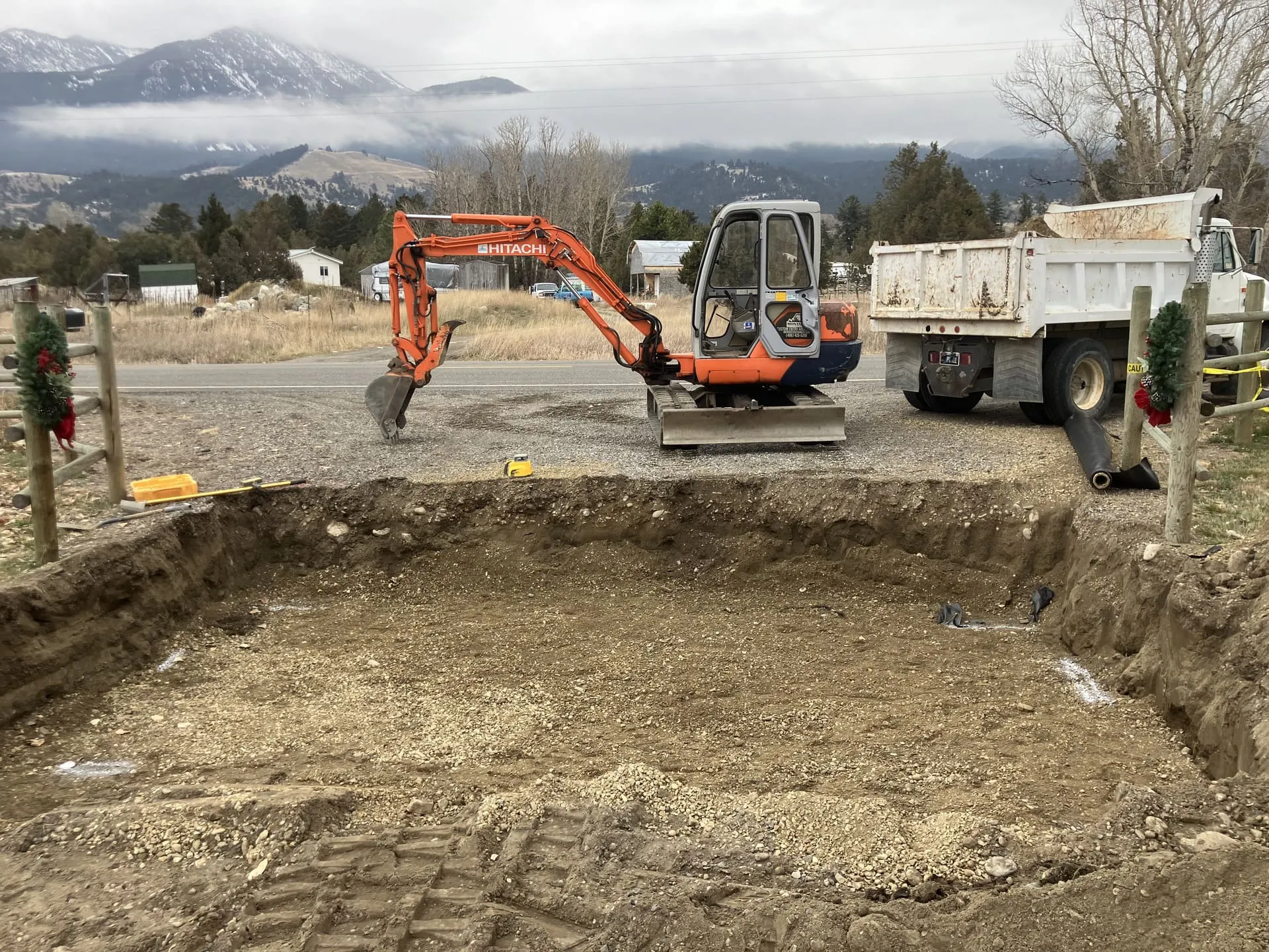 Excavator digging out a section of ground beside a rural road