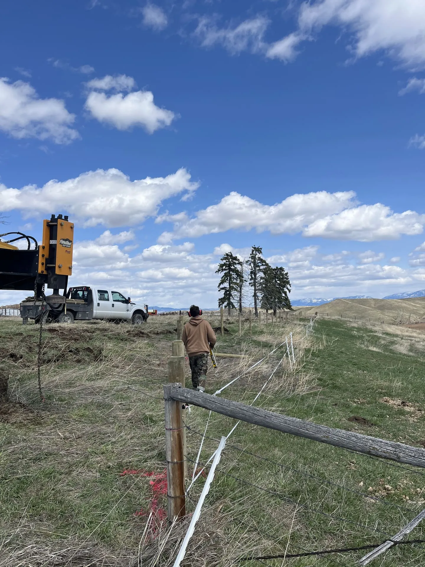 Post pounding a straight fence line on a Montana property
