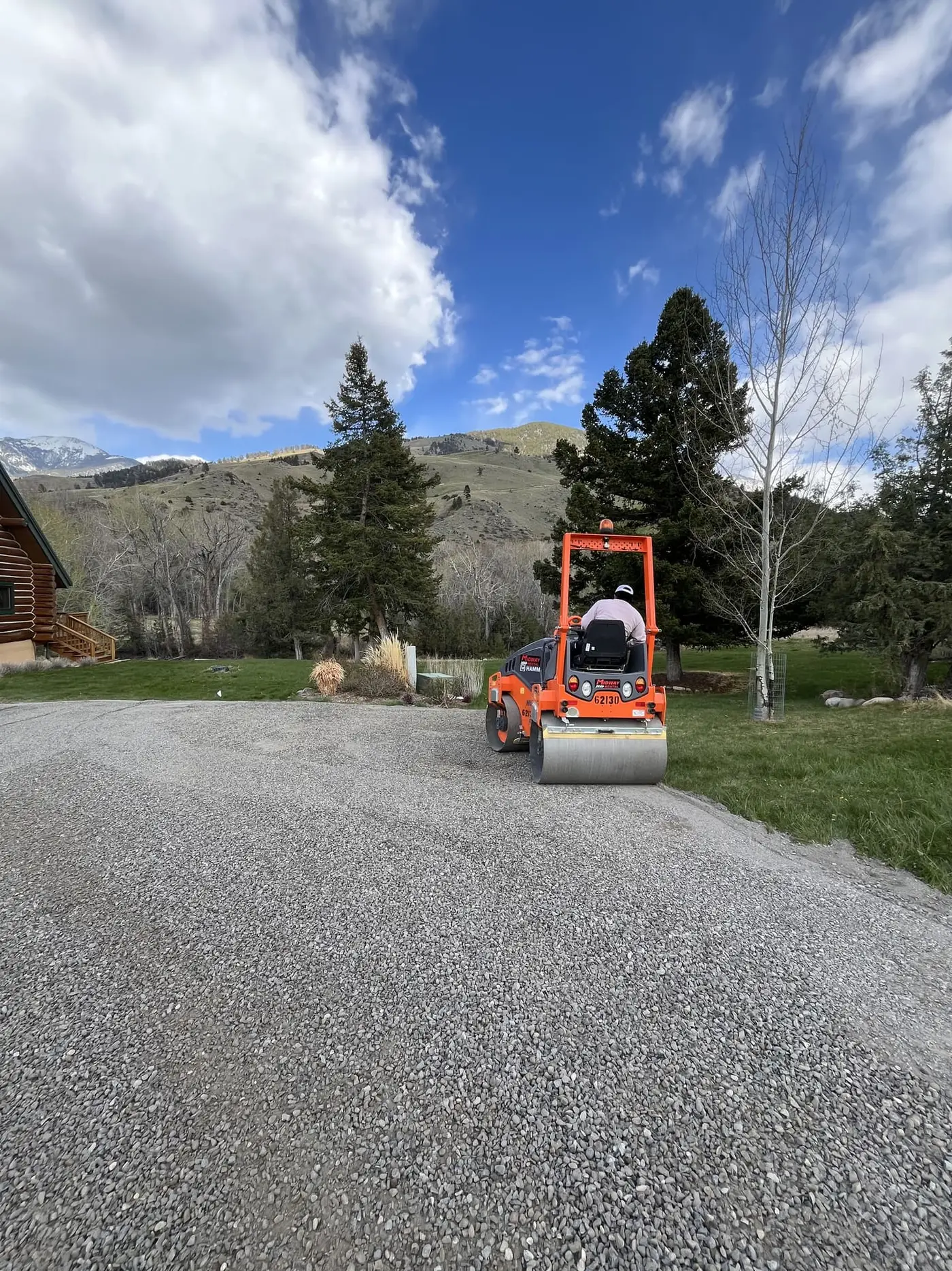 A roller compacting a rebuilt gravel driveway on a Montana property near Mill Creek
